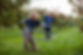 Children enjoying playing hula hoop in the grass next to red apple trees